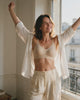 Femme souriante qui s'étire à la fenêtre en portant le Soutien-gorge Jusqu'au Soir