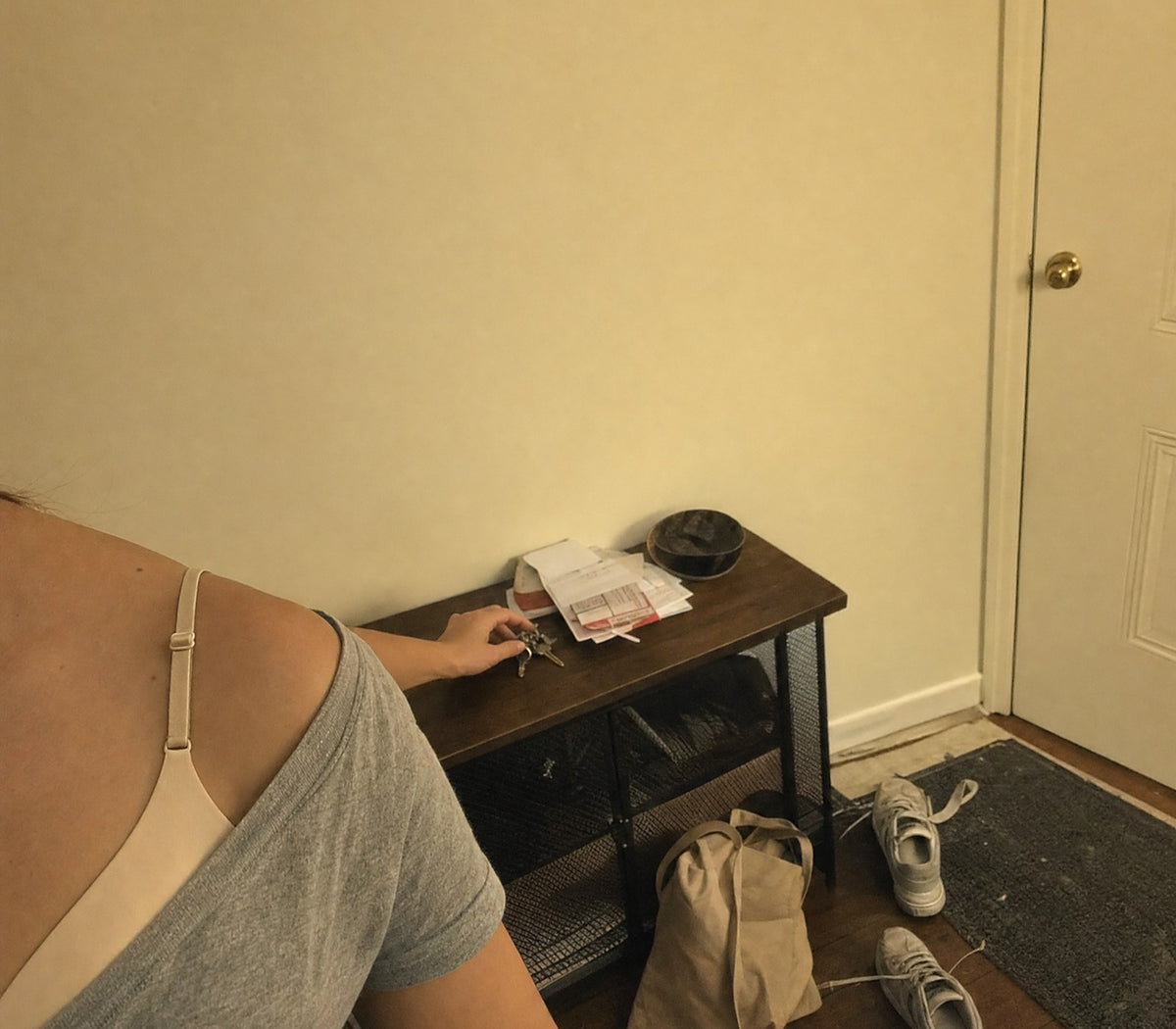 L'entrée le soir, les clés posées, la bretelle visible sous un t-shirt